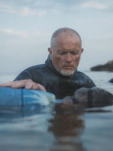 Alain Percevault dans la mer, en combinaison, aux côtés d'une personne qui flotte à la surface