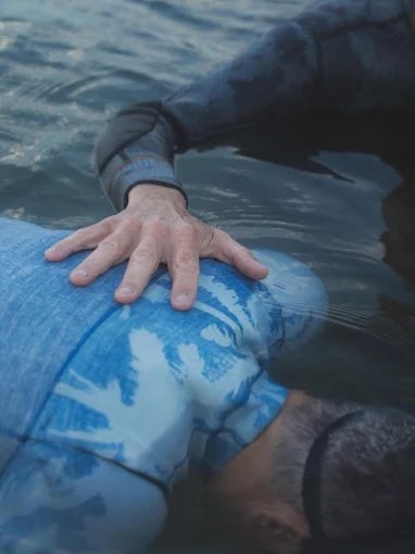 La main d'Alain Percevault posée sur le dos d'une personne qui se relâche à la surface de l'eau